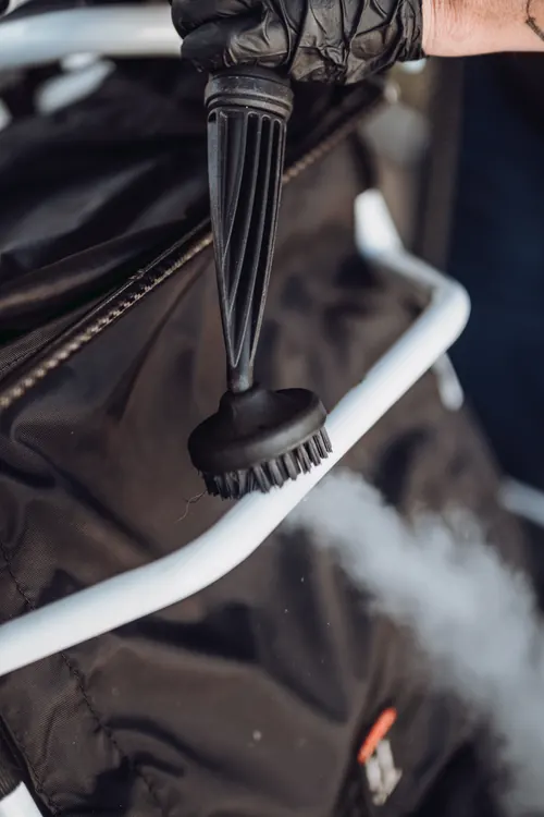 A steam brush head cleaning the frame tubing of a mobility aid.