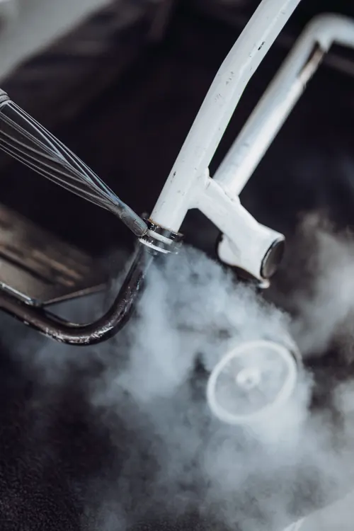 Steam being directed into the frame joint of a mobility walker.