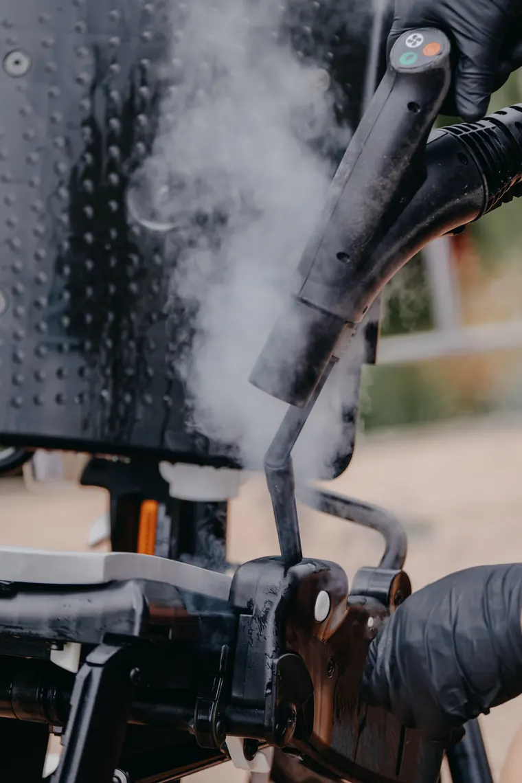 Steam being applied to the backrest and frame of a wheelchair during a professional clean.